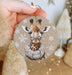 a hand holding a christmas ornament with a picture of a giraffe
