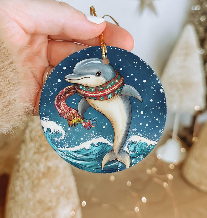 a hand holding a christmas ornament with a dolphin on it