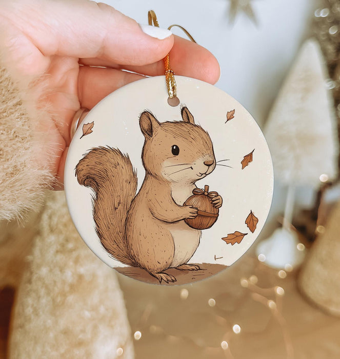 a hand holding a christmas ornament with a squirrel on it