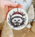 a hand holding a christmas ornament with a hedge on it