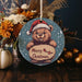 a christmas ornament with a teddy bear holding a sign