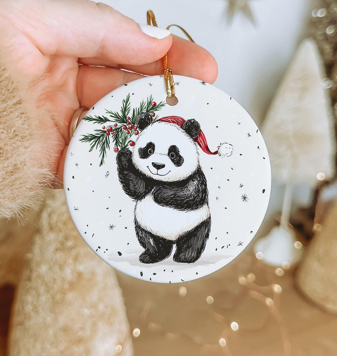 a hand holding a christmas ornament with a panda on it