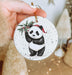 a hand holding a christmas ornament with a panda on it