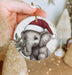 a hand holding a christmas ornament with an elephant wearing a santa hat