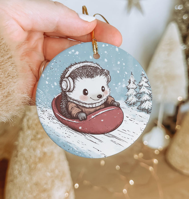 a hand holding a christmas ornament with a hedge riding a sleigh