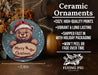 a ceramic christmas ornament with a teddy bear holding a sign