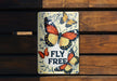 a sign that says fly free on a wooden bench