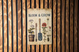 a sign on a wooden wall that says bloom and grow