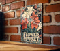 a flower market sign on a brick wall