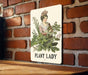 a plant lady sign on a brick wall