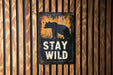 a sign on a wooden wall that says stay wild