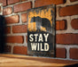a sign that says stay wild on a brick wall