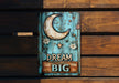 a wooden sign that says dream big on it