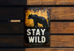 a sign that says stay wild on a wooden wall