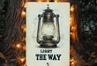 a light the way sign hanging on a tree