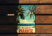 a welcome to paradise sign on a wooden bench