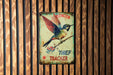 a sign on a wooden wall with a bird on it