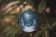 a blue ornament hanging from a christmas tree