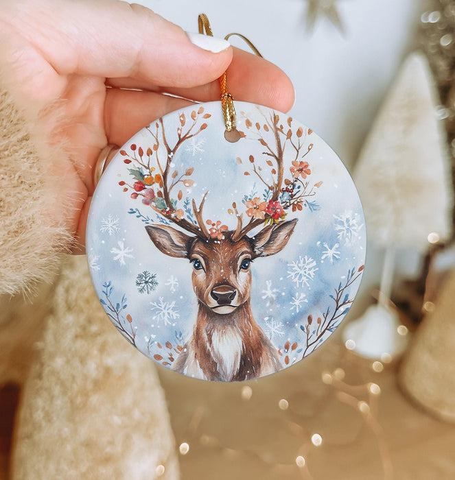 a hand holding a christmas ornament with a deer on it