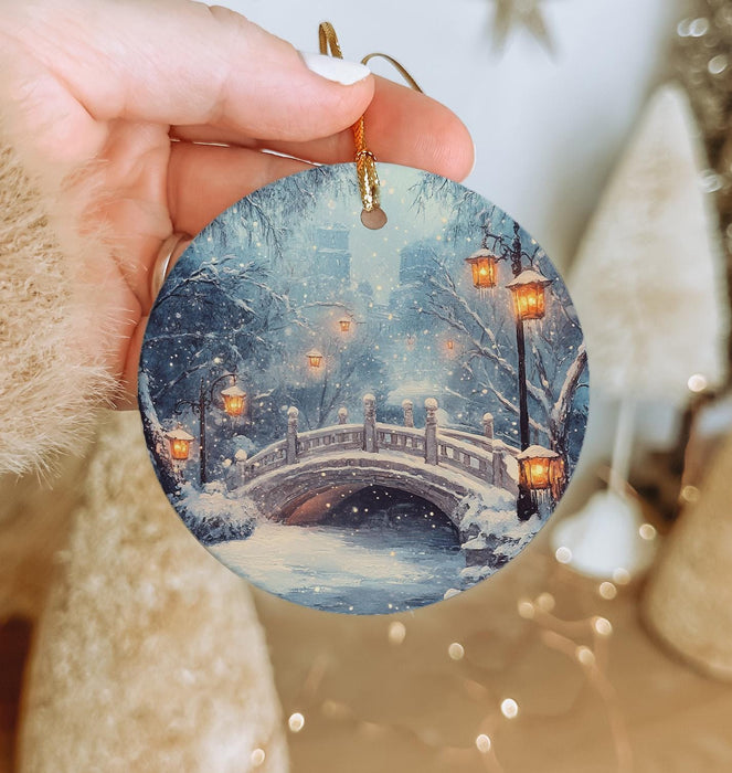 a person holding a christmas ornament with a snowy scene on it
