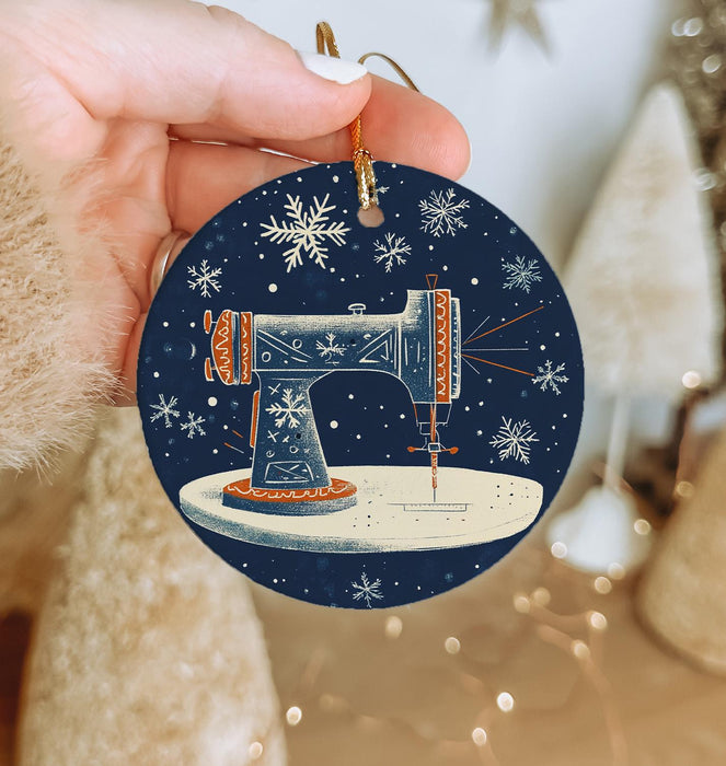 a hand holding a christmas ornament with a sewing machine on it