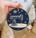 a hand holding a christmas ornament with a sewing machine on it
