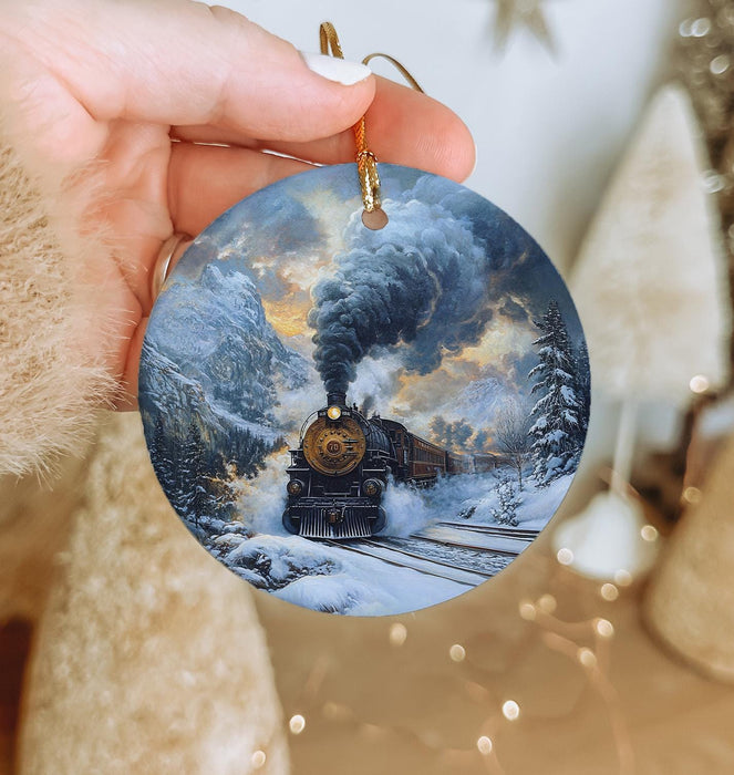 a person holding a christmas ornament with a train on it