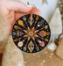 a hand holding a black ornament with colorful designs