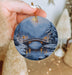 a person holding a christmas ornament with a bridge in the background