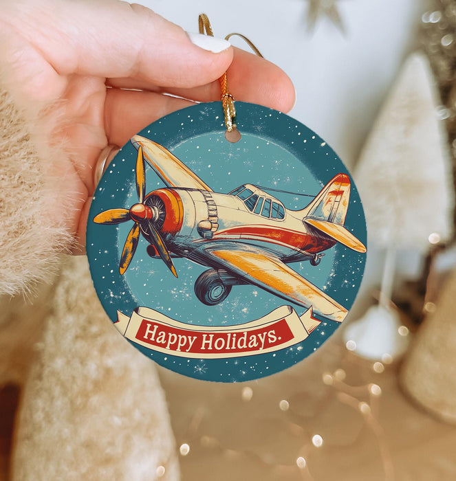 a person holding a christmas ornament with a plane on it