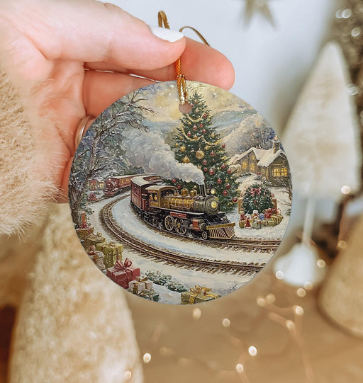 a person holding a christmas ornament with a train on it