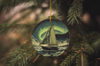 a christmas ornament with a sailboat in the ocean