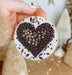 a person holding a ceramic ornament with coffee beans in the shape of a
