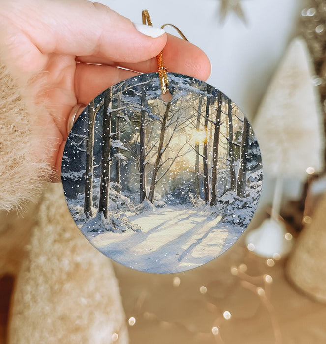 a person holding a christmas ornament with a snowy scene on it