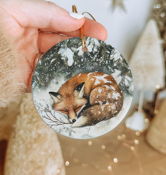 a hand holding a christmas ornament with a picture of a fox