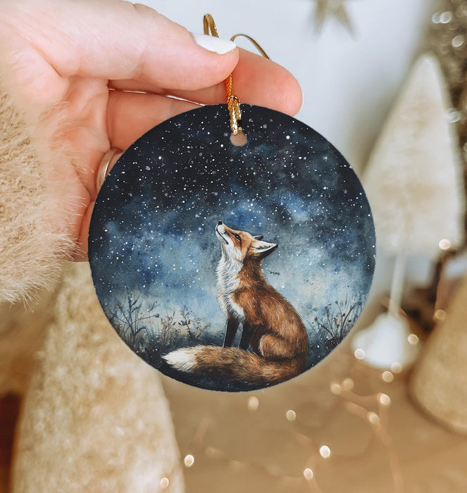a hand holding a christmas ornament with a fox on it