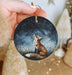 a hand holding a christmas ornament with a fox on it