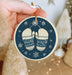 a hand holding a christmas ornament with a pair of slippers on it