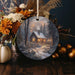 a christmas ornament with a picture of a cabin in the woods