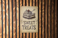 a sign on a wooden wall that says sweet treats