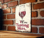 a sign that says wine tasting here on a brick wall