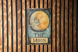 a sign on a wooden wall that says the moon