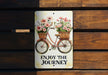 a sign that says enjoy the journey with flowers on a bicycle
