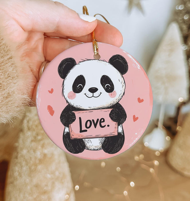 a person holding a pink ornament with a panda bear on it