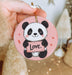 a person holding a pink ornament with a panda bear on it
