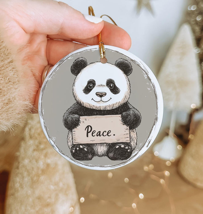 a person holding a christmas ornament with a panda on it