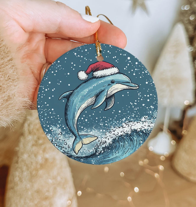 a hand holding a christmas ornament with a dolphin on it