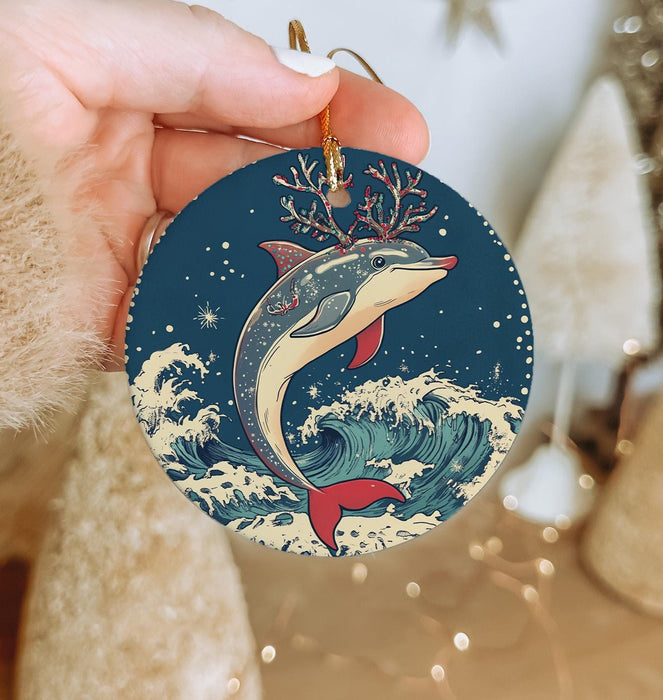 a hand holding a christmas ornament with a dolphin on it