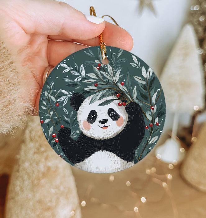 a hand holding a christmas ornament with a panda on it