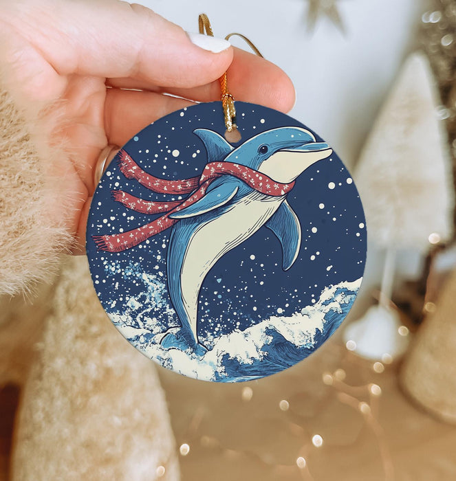 a hand holding a christmas ornament with a dolphin on it